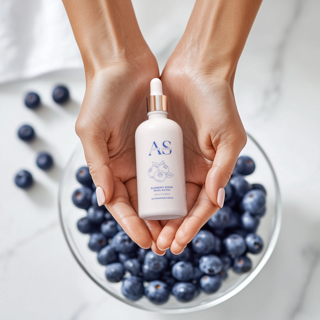 Active Serums 100ml Blueberry Serum held in hands above a bowl of antioxidant-rich fresh blueberries.