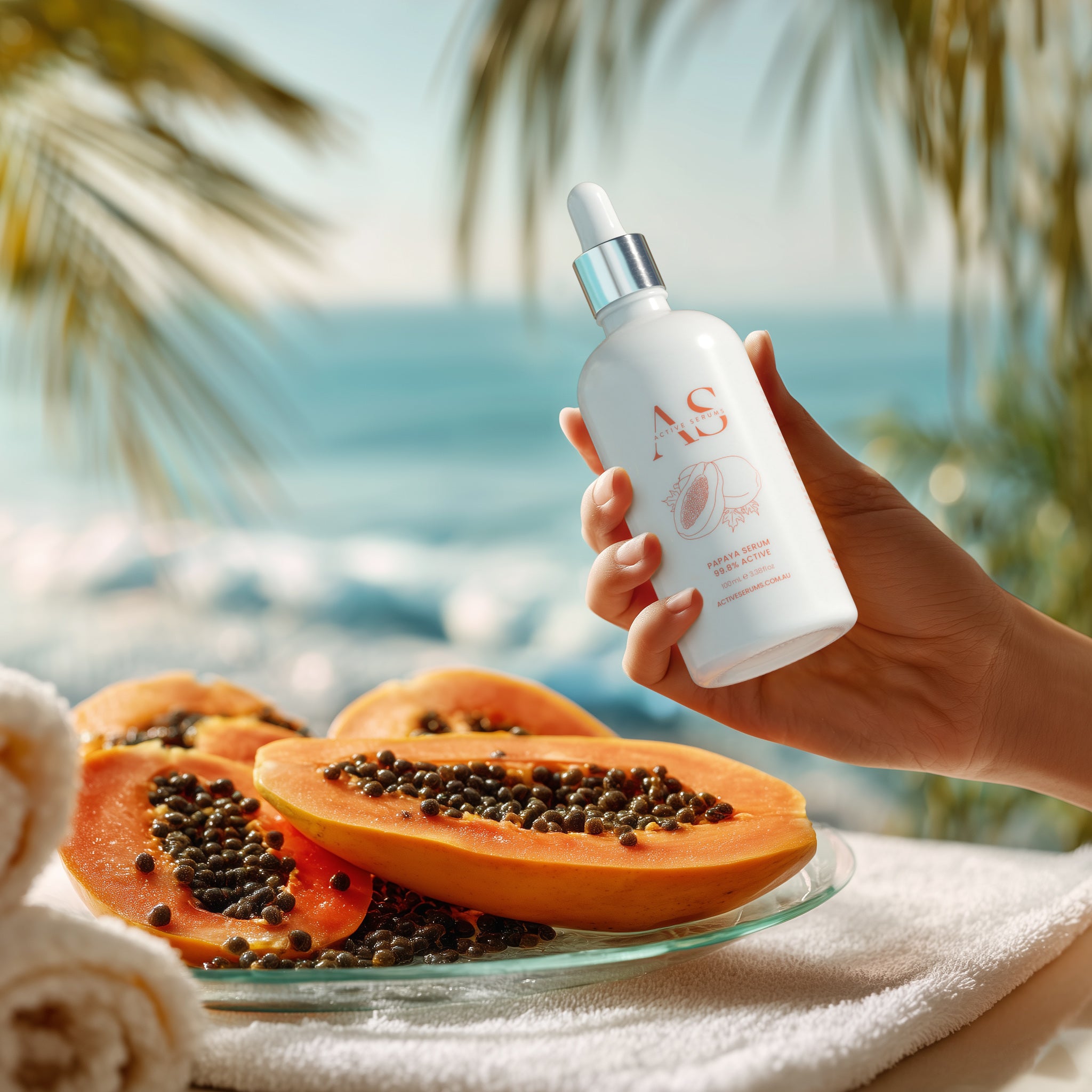 Hand holding Active Serums 100ml Papaya Serum bottle beside fresh papaya and tropical beach backdrop.