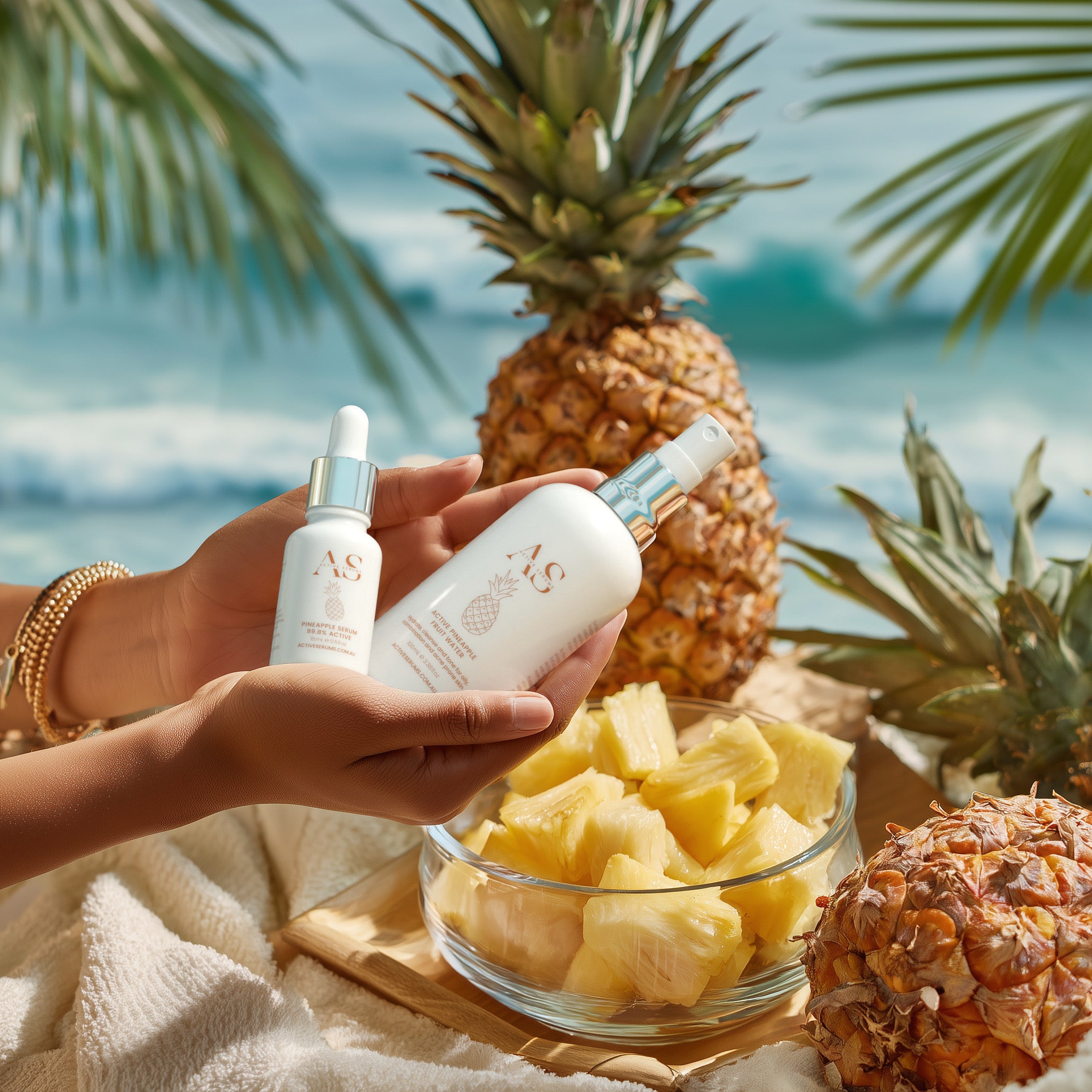 Active Pineapple Duo skincare set held in hands with fresh pineapples on a sunny beach.