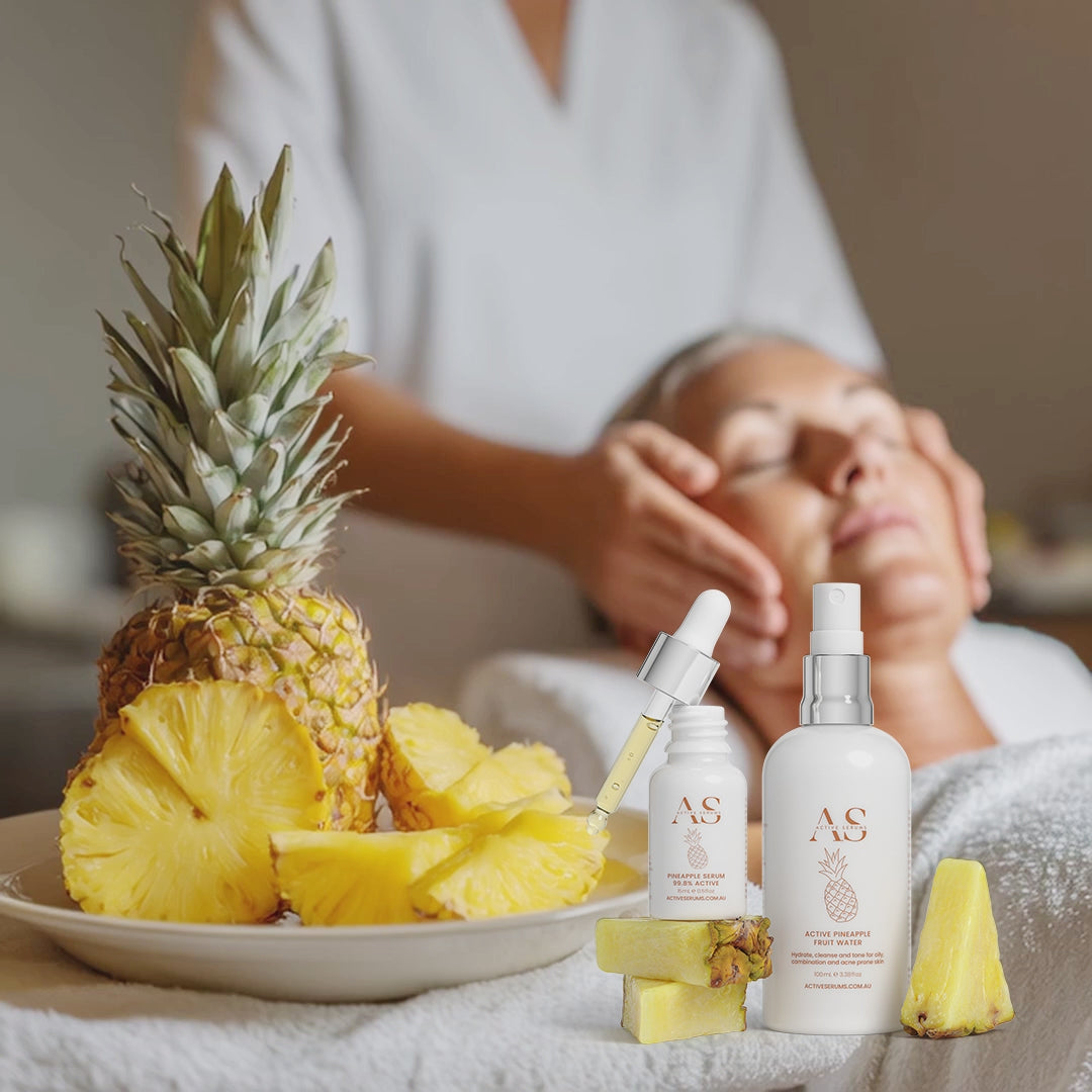 Beauty therapist giving a facial massage next to Active Pineapple Duo skincare and fresh fruit at a spa.