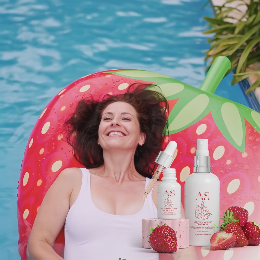 Active Strawberry Duo skincare products featured with a woman on a strawberry pool float in a tropical swimming pool.