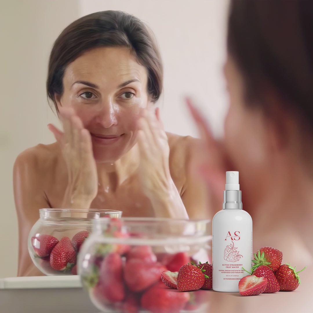 Woman using Active Strawberry Fruit Water for a hydrating cleanse with fresh strawberries in her bathroom.